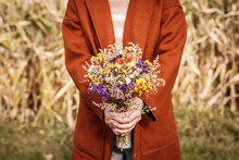 Woman With Red Coat Holding Bouquet Of Dried Flowers In Corn Field
