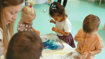 Wall Mural - Multi-cultural nursery school. Toddlers playing with striped straws and milk painting, using nontoxic food coloring for colors. Creative kids activity for using their senses and brain development