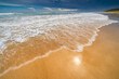 © Austockphoto - Low wide angle view of waves rolling up a golden sandy beach with dark storm clouds overhead