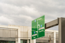 A Large Green Road Sign On An Overhead Metal Boom In Front Of A Grey Sky