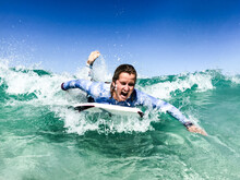 Woman Surfing Wave On A Boogie Board In Clear Ocean