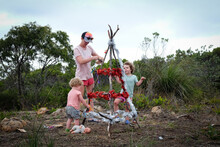 A Mother And Two Toddlers Celebrating Christmas Decorating A Rustic Christmas Tree