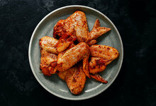 Raw chicken wings marinated in paprika and curry. Copy space. Raw meat in a plate. Dark background, top view.