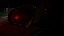 Police lights flashing in back or wing mirror of car, night closeup view of beacon reflection