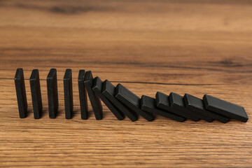 Poster - Black domino tiles falling on wooden table