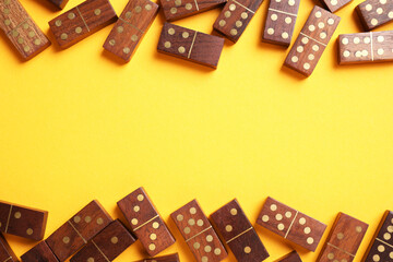 Canvas Print - Wooden domino tiles on yellow background, flat lay. Space for text