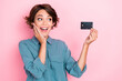 Photo portrait of cute young lady look excited plastic credit card unbelievable wear stylish blue outfit isolated on pink color background