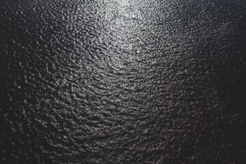 The texture of dark blue water of a river or lake with small waves and ripples on the surface of the water. top view