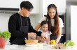 © atitaph - Happy family cooking together in the kitchen. Father, mother and cute little daughter turn vegetables to make salads
