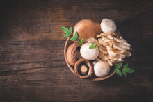 Variety Of Raw Mushrooms On The Wooden Antique Table, Dark Key Atmosphere. Autumn Recipes,  Natural Organic Food, Vegetarian Proteins. Oyster Mushroom, Portobello Mushrooms, Champignons, Copy Space