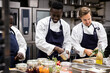 © Maskot - Chefs talking while preparing food in restaurant kitchen
