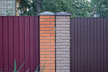 Canvas Print - part of a red brown wall of a fence made of bricks and metal on a rural street