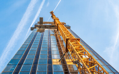 Looking up at the construction site of a high-rise building with a yellow crane