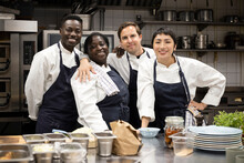 Portrait Of Smiling Multiracial Chefs Standing In Kitchen Counter At Restaurant