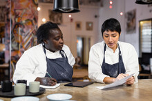 Female Colleagues Discussing Menu Card At Table In Restaurant