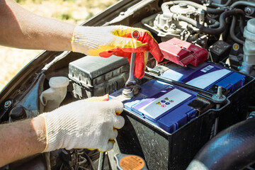 Car battery replacement. The car mechanic repairs the car, unscrews the battery mount