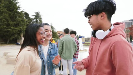 Wall Mural - Group Of Three Multiethnic Teenage Students Standing Outside College Building tlking bout homeworks, at the background five friends laughing.