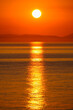 Reflection of the sun rising from behind the mountains on the horizon on the surface of sea water.