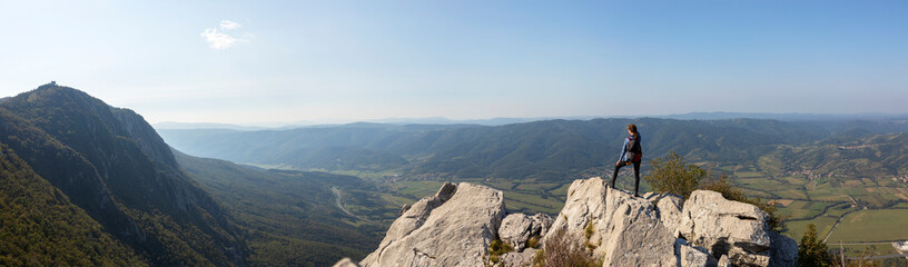 woman hiker standing on a top of a mountain looking the valley bellow