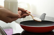 Woman cooking with coconut oil on induction stove, closeup