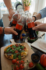 Portrait of four friends celebrating event drinking cola and eating home made pizza.