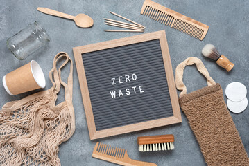 Zero waste concept. Bath accessories and kitchen utensils are eco-friendly. Zero waste inscription on letter board. Gray grunge background. Top view, flat lay.