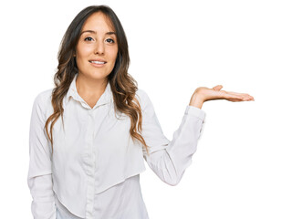 Wall Mural - Young brunette woman wearing casual clothes smiling cheerful presenting and pointing with palm of hand looking at the camera.