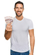 © Krakenimages.com - Handsome man with beard holding 50 mexican pesos banknotes looking positive and happy standing and smiling with a confident smile showing teeth