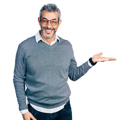 Sticker - Middle age hispanic with grey hair wearing glasses smiling cheerful presenting and pointing with palm of hand looking at the camera.