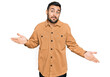 © Krakenimages.com - Young hispanic man wearing casual clothes clueless and confused expression with arms and hands raised. doubt concept.