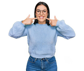 young hispanic woman wearing casual clothes and glasses smiling cheerful showing and pointing with f