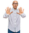 © Krakenimages.com - Bald man with beard wearing business shirt and glasses afraid and terrified with fear expression stop gesture with hands, shouting in shock. panic concept.