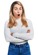 Young blonde woman with arms crossed gesture in shock face, looking skeptical and sarcastic, surprised with open mouth