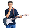 Young handsome man playing electric guitar covering mouth with hand, shocked and afraid for mistake. surprised expression