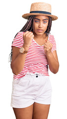 Sticker - Young african american woman with braids wearing summer hat ready to fight with fist defense gesture, angry and upset face, afraid of problem