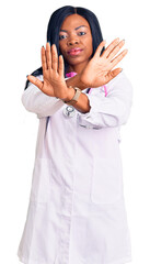 Poster - Young african american woman wearing doctor stethoscope rejection expression crossing arms doing negative sign, angry face