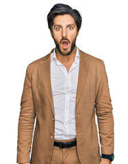 Wall Mural - Young hispanic man wearing business clothes afraid and shocked with surprise and amazed expression, fear and excited face.