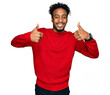 Young african american man with beard wearing casual winter sweater success sign doing positive gesture with hand, thumbs up smiling and happy. cheerful expression and winner gesture.