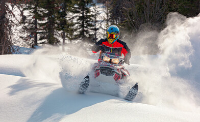 Snowmobile riding with fun in deep snow powder during backcountry tour. Extreme sport adventure, outdoor activity during winter holiday on ski mountain resort