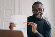 © VK Studio - Pleasant immersed in work African male home office worker holds business meeting online
