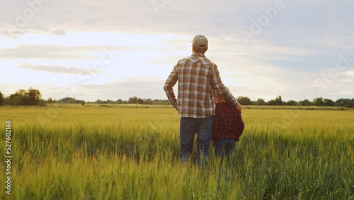 Fototapete Farmer and his son in front of a sunset agricultural landscape. Man and a boy in a countryside field. Fatherhood, country life, farming and country lifestyle.
