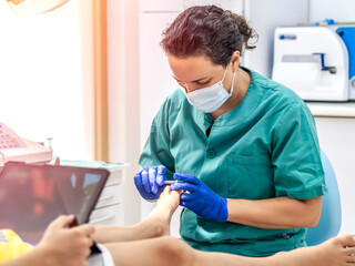 Female podiatrist doing chiropody in her podiatry clinic. Selective focus