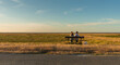 © pinkyone - People (couple) sit on a bench in the middle of nowhere. Flat, remote, peaceful, meadow landscape.