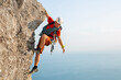 © Studio Peace - Young male climber climbs a difficult route with a view of the sea at sunset.