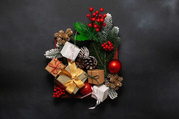 Wall Mural - Wooden box with bright Christmas decorations and gift boxes on black stone background top view. Festive Christmas and New Year composition.