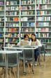 © LIGHTFIELD STUDIOS - teenage students reading books near bookshelves in library.
