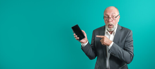 Application advertising. Adult man in glasses showing black blank smartphone screen recommending website posing in studio green background