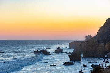 Rocky coastline of El Matador beach at sunset during high tide