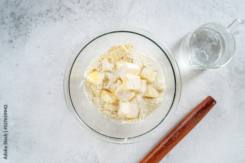 Pastry Cold Methods cubes cold butter in a glass bowl with all-purpose flour in preparation ...
