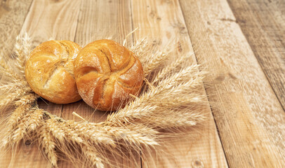 Fresh bread and wheat on a wooden table 